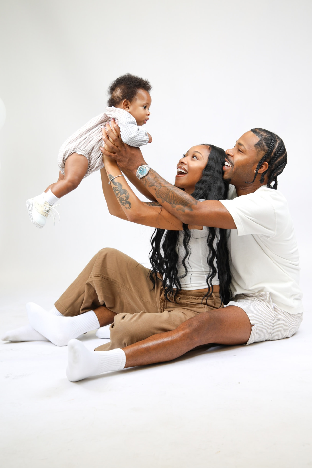 Parents lifting their baby up in the air, laughing