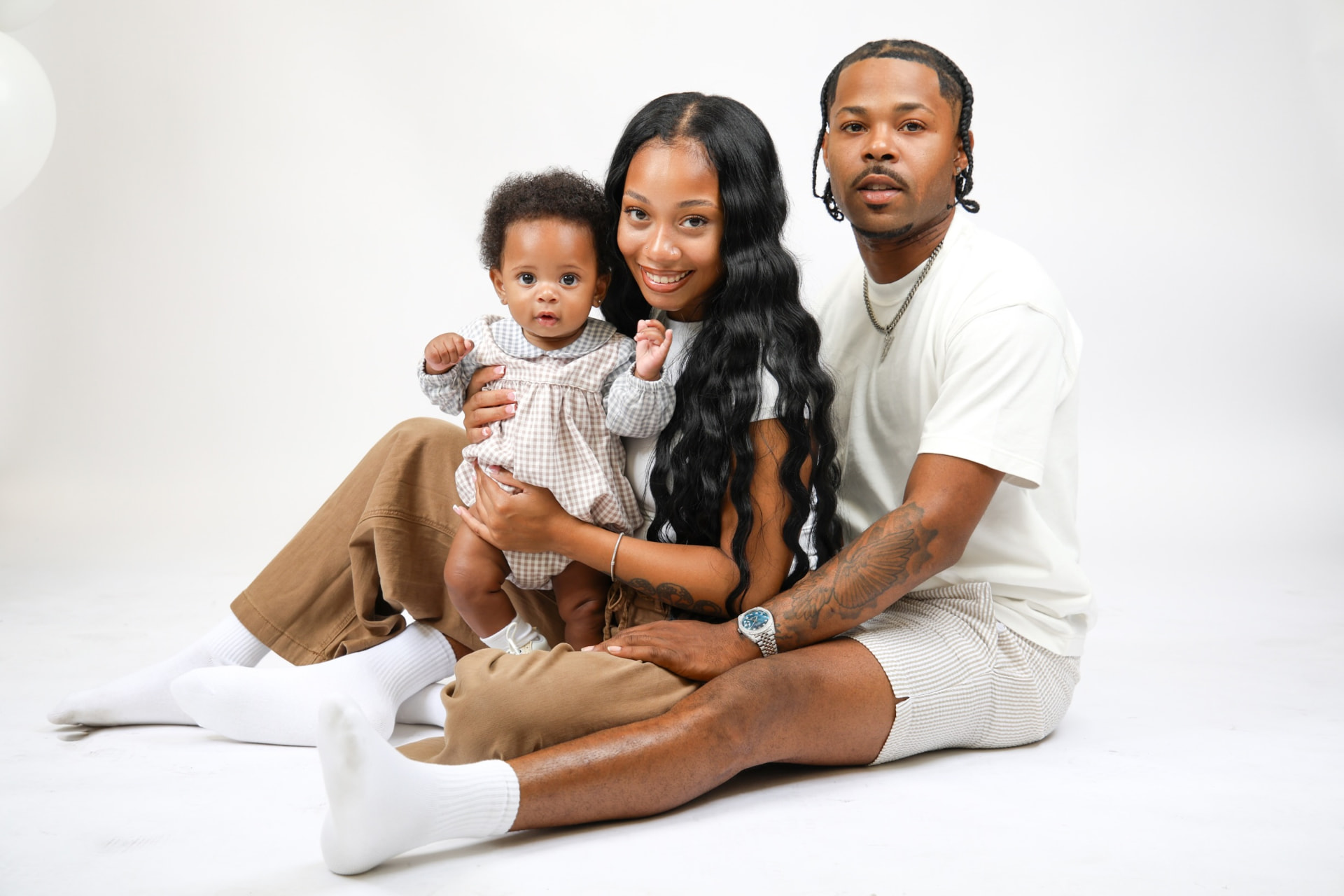 A mom, dad and baby sitting together for a family portrait